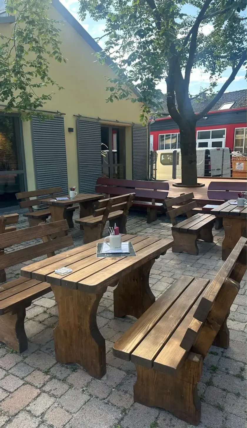 Biergartenbänke aus Holz unter alten Bäumen