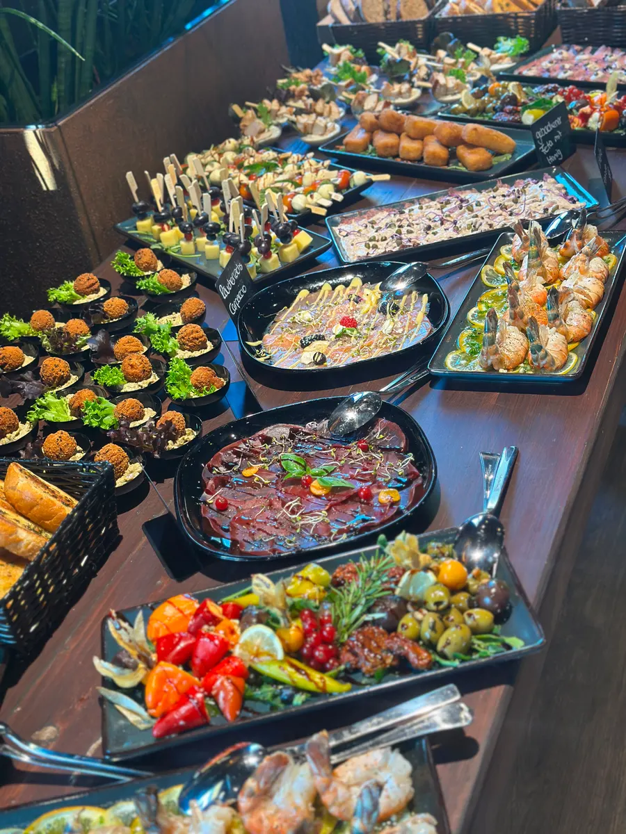 Reich gedecktes Fingerfood-Buffet mit Carpaccio, Spießen, Antipasti und Brotkorb