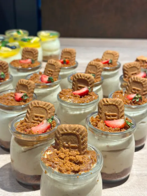 Karamellkeks-Cheesecakes im Glas mit Keksbröseln und Erdbeeren